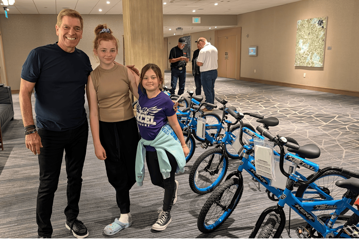 Dan Perdue, President of LEVEL 12, standing with two young recipients of new bicycles during a corporate team building donation.